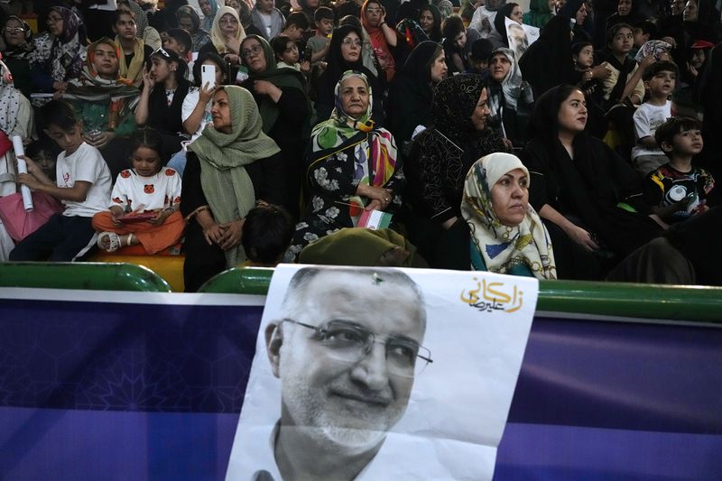 Supporters of Tehran Mayor Alireza Zakani, shown in the poster, a candidate for the June 28 presidential election, attend his campaign rally in Tehran, Iran, Sunday, June 23, 2024. (AP Photo/Vahid Salemi)