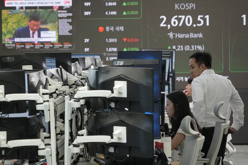 Currency traders watch monitors near a screen showing the Korea Composite Stock Price Index (KOSPI) at the foreign exchange dealing room of the KEB Hana Bank headquarters in Seoul, South Korea, Friday, Aug. 30, 2024. (AP Photo/Ahn Young-joon)