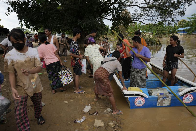 Local residents carry their belongings along a flooded road, in Naypyitaw, Myanmar, Tuesday, Sept. 17, 2024. (AP Photo/Aung Shine Oo)