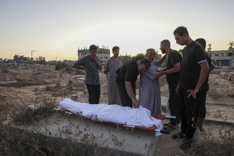 Palestinian mourners prepare to bury their loved one at the cemetery in Deir al-Balah, Gaza Strip, Friday, Aug. 9, 2024. (AP Photo/Abdel Kareem Hana)