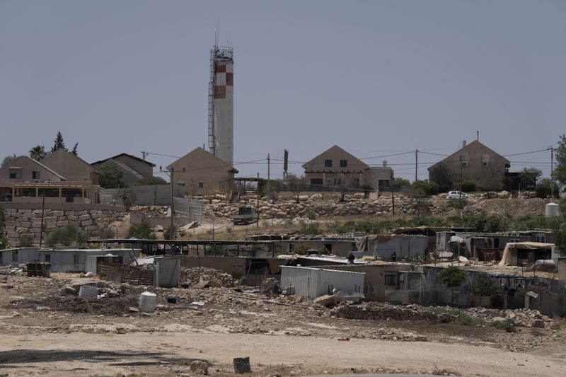 FILE - Caravans and simple structures for residents of the West Bank Bedouin village of Umm al-Khair, foreground, are seen near the Israeli settlement of Carmel, background, on July 10, 2024. (AP Photo/Maya Alleruzzo, File)