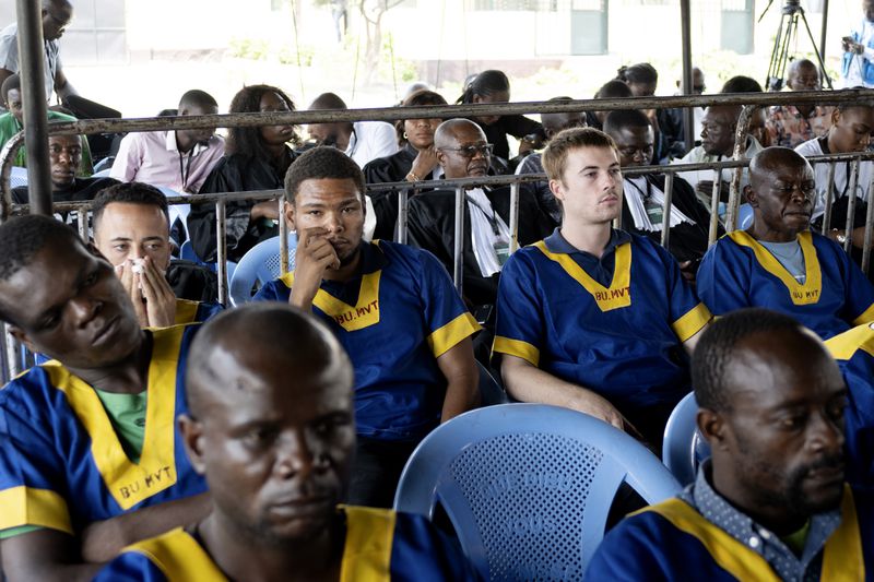 Back row, Tyler Thompson, 2nd left, Marcel Malanga, center, and Benjamin Reuben Zalman-Polun, 2nd right, all American citizens, attend a court verdict in Congo, Kinshasa, Friday Sept .13, 2024, on charges of taking part in a coup attempt in May 2024. (AP Photo/Samy Ntumba Shambuyi)