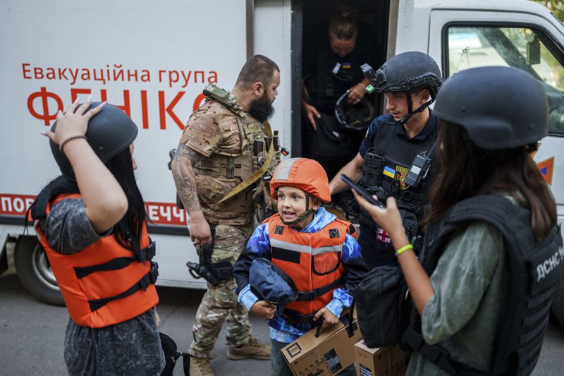 Bohdan Scherbyna, 9, with his mother Maryna Scherbyna, 45, and sister Angelina Scherbyna, 14, left, arrive in an armoured van belonging to the emergency service Fenix team during the evacuation of local people from Selidove to safe areas, in Pokrovsk, Donetsk region, Ukraine, on Tuesday, Aug. 20, 2024. (AP Photo/Evgeniy Maloletka)