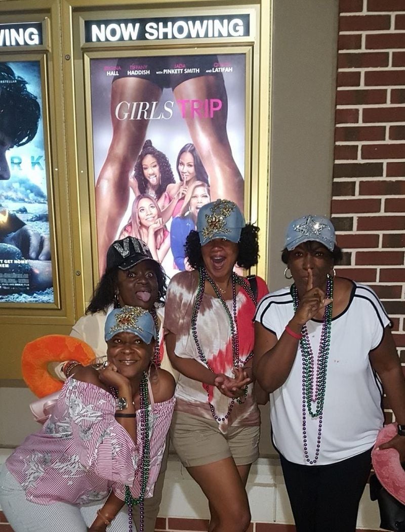 Lisa Haygood, Shelia Howell-Reynolds, Tonya Hood and Tonya Mahone Williams pose beneath a poster for the movie, "Girls Trip," about four Black women who travel to New Orleans for the Essence Festival. “ 