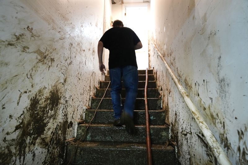 Contractor Joshua Taylor walks up stairs covered in mud leading to the basement of a funeral home that was flooded in the aftermath of Hurricane Helene while working to clean up the building Saturday, Oct. 5, 2024, in Newport, Tenn. (AP Photo/Jeff Roberson)