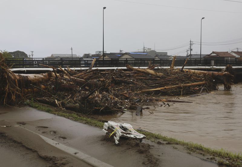 Debris is piled along a bridge over the Kawarada river near the city hall in Wajima, Japan, Sunday, Sept. 22, 2024, following heavy rain in central Japan's Noto peninsula area. (Yasuko Kishimoto/Kyodo News via AP)