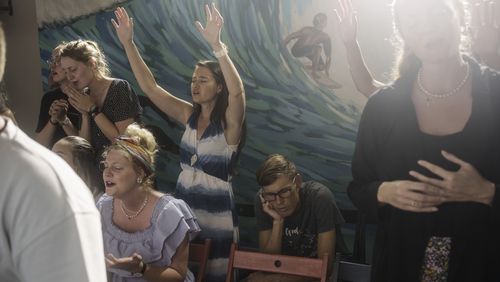 Marielle Louw, raised hands, and Andries Louw, missionaries from South Africa, pray during a worship service at Surf Church in Matosinhos beach in the suburbs of Porto, Portugal on Sunday, Aug. 18, 2024. (AP Photo/Luis Andres Henao)