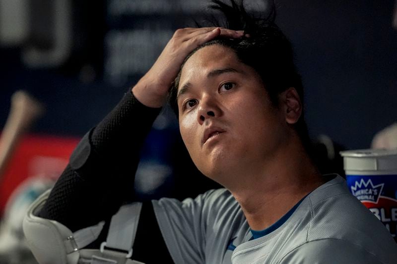 Los Angeles Dodgers two-way player Shohei Ohtani (17) sits in the dugout in the fourth inning of a baseball game against the Atlanta Bravess, Friday, Sept. 13, 2024, in Atlanta. (AP Photo/Mike Stewart)