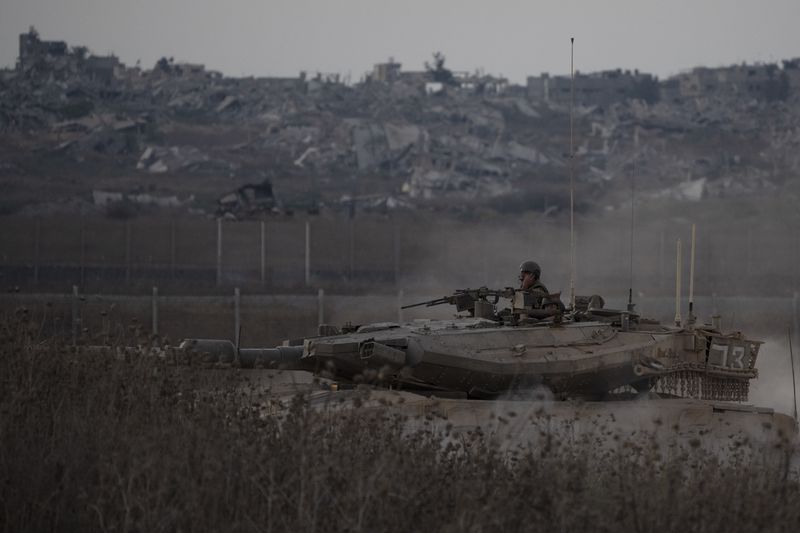 Israeli soldiers move on the top of a tank near the Israeli-Gaza border, as seen from southern Israel, Wednesday, Aug. 21, 2024. (AP Photo/Leo Correa)