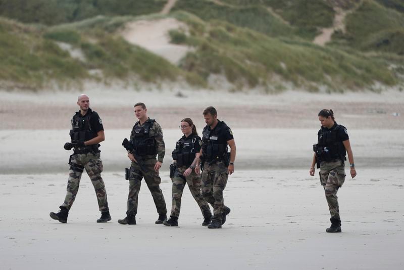 Police officers guard at the Wimereux beach, France, Wednesday, Sept. 4, 2024. Another boat carrying several dozen people is making another attempt to cross the English Channel from northern France just a day after 12 migrants died. (AP Photo/Nicolas Garriga)