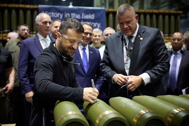 Ukrainian President Volodymyr Zelenskyy, left, is watched by Rich Hansen, the commander's representative for the Scranton Army Ammunition Plant, while signing military ordnance in Scranton, Pa., Sunday, Sept. 22, 2024. (Office of the Ukrainian Presidency via AP)