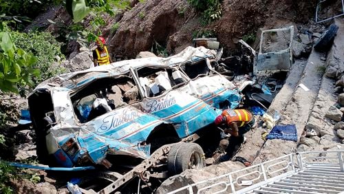 Rescue workers look for the victims and wounded passengers from the wreckage of a bus that fell into a ravine, near Kahuta, Pakistan, Sunday, Aug. 25, 2024. (AP Photo/Mohammad Yousaf)