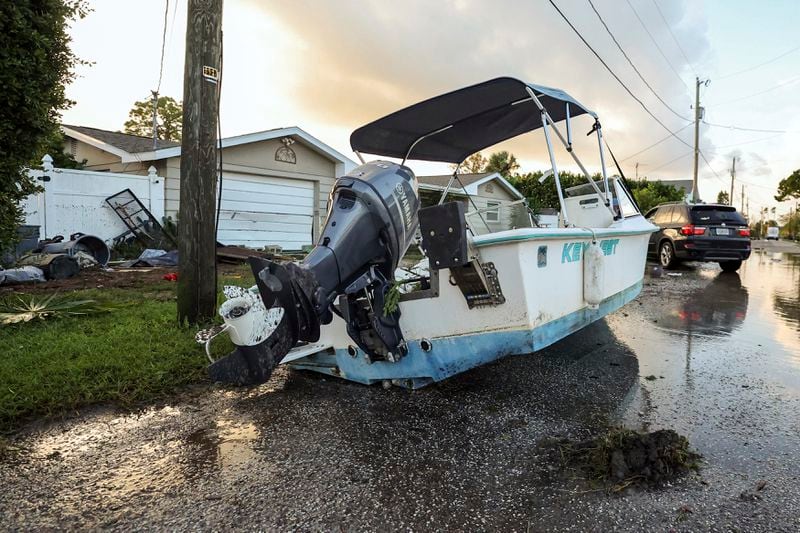 A boat rests on a street after being relocated during flooding caused by Hurricane Helene Friday, Sept. 27, 2024, in Hudson, Fla. (AP Photo/Mike Carlson)