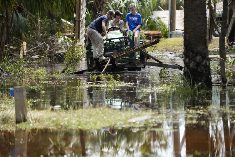 People move debris from a damaged home in the aftermath of Hurricane Helene, in Horseshoe Beach, Fla., Saturday, Sept. 28, 2024. (AP Photo/Stephen Smith)