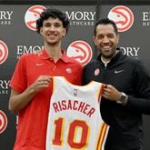 The Hawks' Zaccharie Risacher (left) and general manager Landry Fields hold up the rookie's jersey during a press conference at Emory Sports Medicine Complex, Friday, June 28, 2024, in Brookhaven. (Hyosub Shin / Hyosub.Shin@ajc.com)