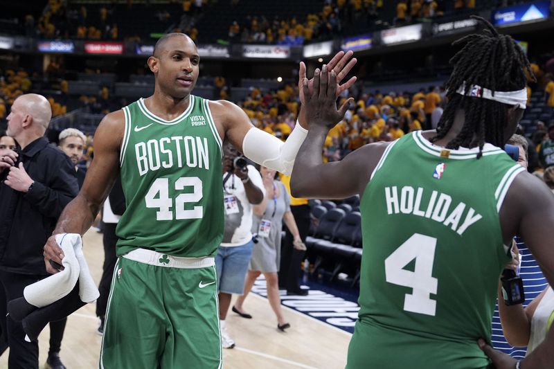 Boston Celtics center Al Horford (42) celebrates with teammate guard Jrue Holiday (4) after Game 3 of the NBA Eastern Conference basketball finals against the Indiana Pacers, Saturday, May 25, 2024, in Indianapolis. The Celtics won 114-111.(AP Photo/Michael Conroy)
