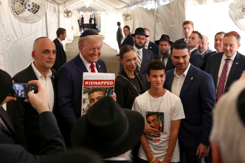 Republican presidential nominee former President Donald Trump poses for photos with members of the Chabad Lubavitch after visiting the gravesite of Rabbi Menachem Mendel Schneerson, Monday, Oct. 7, 2024, in New York. (AP Photo/Yuki Iwamura)