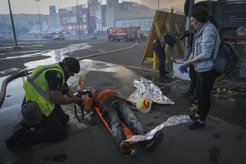 A police officer registers a dead body after two Russian guided bombs hit a large construction supplies store in Kharkiv, Ukraine, Saturday, May 25, 2024. (AP Photo/Andrii Marienko)