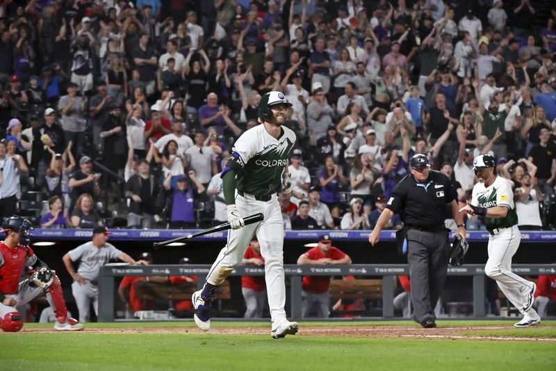 Colorado Rockies' Ryan McMahon heads to first on a bases-loaded walk, driving in Jake Cave, right rear, with the winning run against the Washington Nationals in a baseball game Saturday, June 22, 2024, in Denver. (AP Photo/Geneva Heffernan)