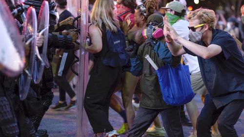 Protesters dodge tear gas and police Tuesday after the 9 p.m. curfew  in downtown Atlanta as protests continued for a fifth day.