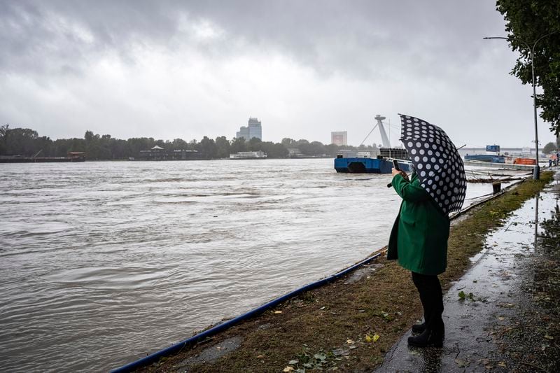 A woman takes a photo of high levels of the Danube river in Bratislava, Slovakia, Sunday, Sept. 15, 2024. (AP Photo/Tomas Hrivnak)