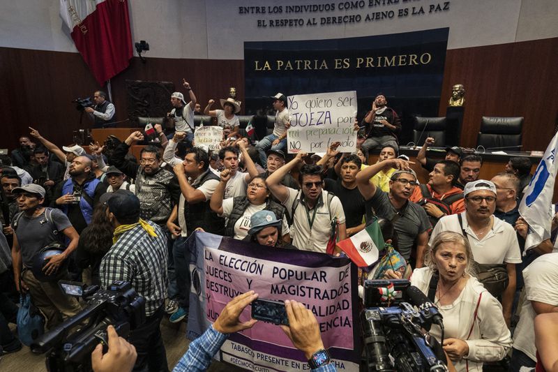 Protesters interrupt a Senate session in which lawmakers were debating the government's proposed judicial reform, which would make judges stand for election, in Mexico City, Tuesday, Sept. 10, 2024. (AP Photo/Felix Marquez)