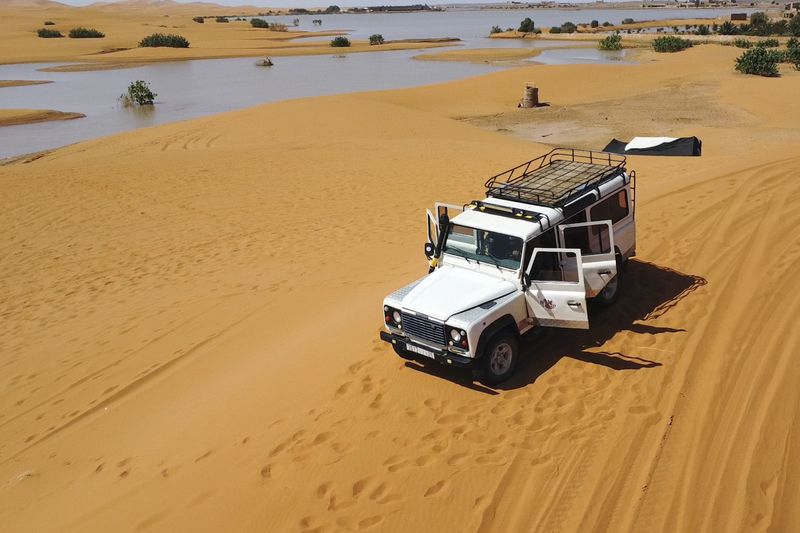 A vehicle transports tourists on sand dunes next to a lake caused by heavy rainfall in the desert town of Merzouga, near Rachidia, southeastern Morocco, Wednesday, Oct. 2, 2024. (AP Photo)