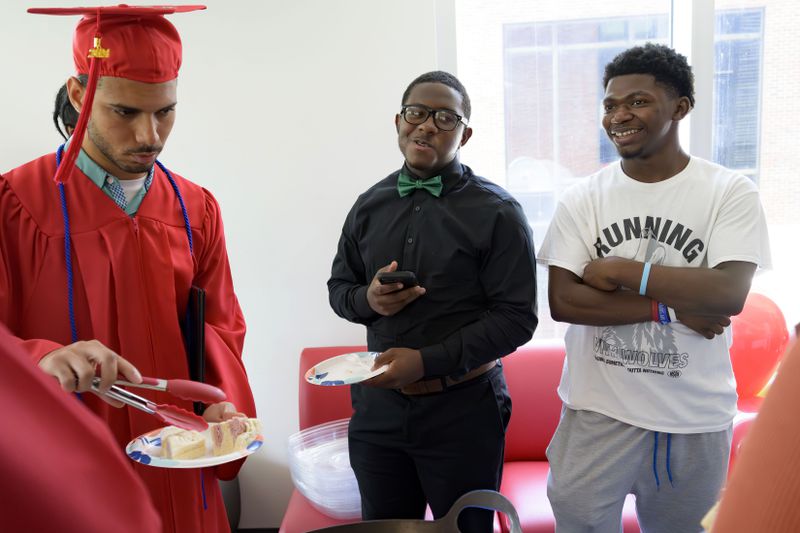 Ke'Daryl Sentmore, 17, right, is a participant in the Youth Empowerment Project (YEP) works program along with Makhi Trumble, 16, center, and they both helped out with food at a graduation of fellow students including Darel Godinez Rodriguez, left, in New Orleans, Thursday, June 27, 2024. (AP Photo/Matthew Hinton)