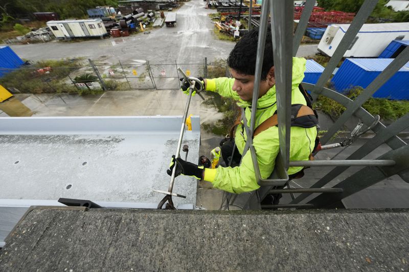 Delwyn Bodden, a worker for the Southeast Louisiana Flood Protection Authority-West climbs a ladder up a floodgate to lock it closed along the Harvey Canal, just outside the New Orleans city limits, in anticipation of Tropical Storm Francine, in Harvey, La., Tuesday, Sept. 10, 2024. (AP Photo/Gerald Herbert)