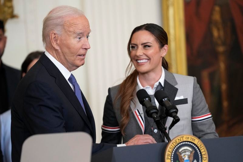 President Joe Biden speaks as Ali Krieger, right, a member of the 2023 NWSL championship NJ/NY Gotham FC team, listens during an event in the East Room of the White House in Washington, Monday, Sept. 23, 2024, to welcome the team and celebrate their championship. (AP Photo/Susan Walsh)