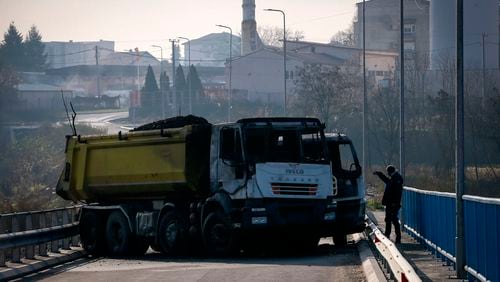 FILE - A man takes photos of a burnt-out truck, part of a barricade on the bridge in Mitrovica, Kosovo, Thursday, Dec. 29, 2022. (AP Photo/Visar Kryeziu, File)