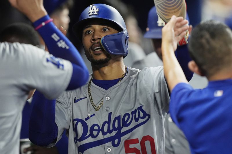 Los Angeles Dodgers' Mookie Betts (50) scores on a sacrifice hit by Freddie Freeman during the fifth inning of a baseball game against the Miami Marlins, Tuesday, Sept. 17, 2024, in Miami. (AP Photo/Marta Lavandier)