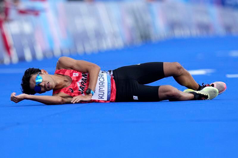 Japan's Yutaka Kumagai lies on the ground after the men's marathon T12 finish at the 2024 Paralympic Games in Paris, France, Sunday, Sept. 8, 2024. (AP Photo/Thibault Camus)