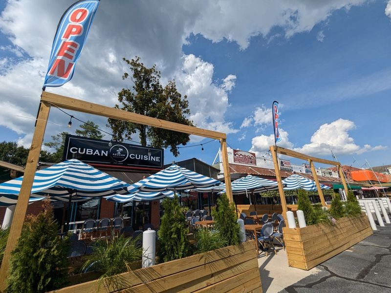 The patio at Azucar Cuban Cuisine offers comfortable, umbrella-covered seating surrounded by young palm trees. (Paula Pontes for The Atlanta Journal-Constitution)