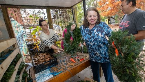 Volunteers at Oakhurst Garden, including Emily Audino, Anne Marie Happe and Flavio Adamo, prepare to add pine cones, magnolia pods and other decorative items to wreaths as part of a fundraiser to help support the Wylde Center. The center and its five gardens are expanding. (Jenni Girtman for Atlanta Journal-Constitution)