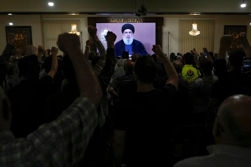 Hezbollah supporters raise their fists and cheer as they watch a speech given by Hezbollah leader Sayyed Hassan Nasrallah on a screen during a ceremony to commemorate the death of senior Hezbollah commander Taleb Sami Abdullah, 55, who was killed last week by an Israeli strike in south Lebanon, in the southern Beirut suburb of Dahiyeh, Lebanon, Wednesday, June 19, 2024. (AP Photo/Bilal Hussein)