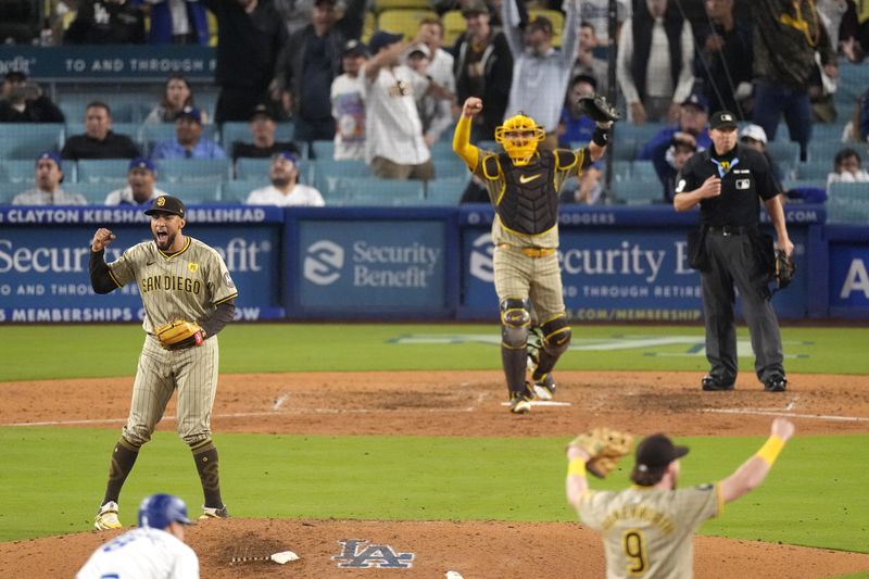 San Diego Padres relief pitcher Robert Suarez, left, celebrates along with catcher Kyle Higashioka, center, and Jake Cronenworth, right, as Los Angeles Dodgers' Kiké Hernández stands on second base after the Padres clinched a playoff spot with a triple play to end their baseball game against the Los Angeles Dodgers, Tuesday, Sept. 24, 2024, in Los Angeles. (AP Photo/Mark J. Terrill)