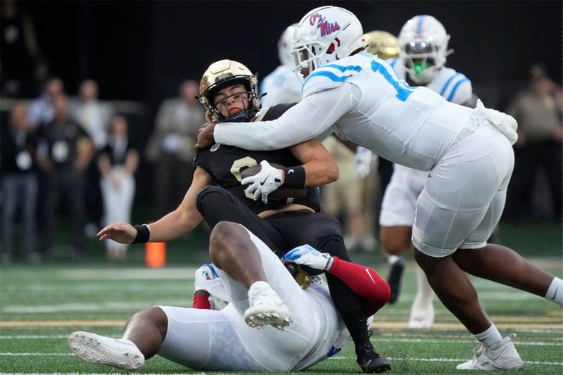 Wake Forest quarterback Hank Bachmeier, center, is sacked by Mississippi defensive tackle JJ Pegues, bottom, and Jared Ivey, right, during the first half of an NCAA college football game in Winston-Salem, N.C., Saturday, Sept. 14, 2024. (AP Photo/Chuck Burton)