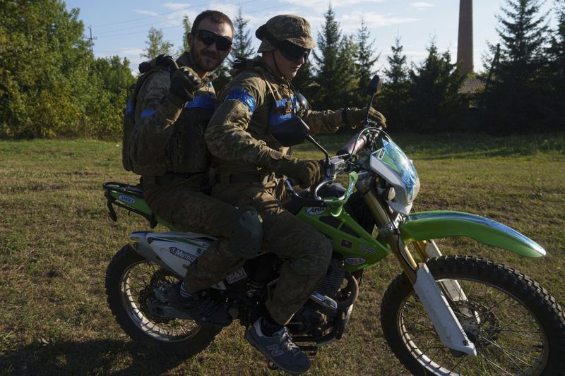 Ukrainian servicemen ride a motorcycle towards the Russian-Ukrainian border in Sumy region, Ukraine, Thursday, Aug. 15, 2024. (AP Photo/Evgeniy Maloletka)