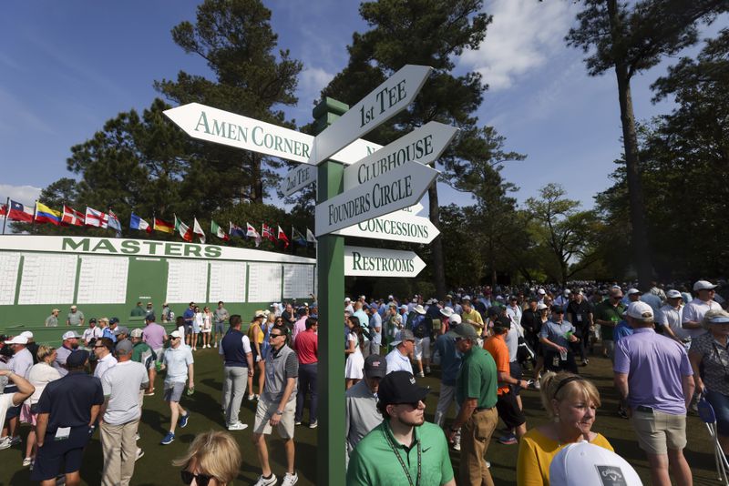 Patrons at Augusta National walk around a sign posting directions to famous areas of interest.