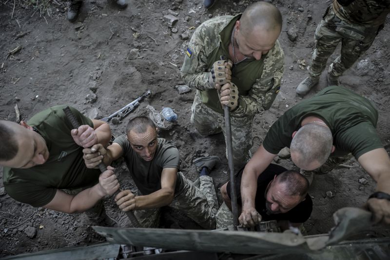 In this photo provided by Ukraine's 24th Mechanised Brigade press service, servicemen of 24th mechanised brigade repair tracks of a BRM1k infantry fighting vehicle near Chasiv Yar town, in Donetsk region, Ukraine, Saturday, Aug. 17, 2024. (Oleg Petrasiuk/Ukrainian 24th Mechanised Brigade via AP)