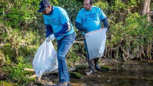 Atlanta Councilmember Dustin Hillis (R) and Mayor of Atlanta Andre Dickens (L) bag trash along  Proctor Creek during Sweep The Hooch day in Atlanta Saturday, March 26, 2022. Proctor Creek runs through Atlanta and ultimately empties into the Chattahoochee River. STEVE SCHAEFER FOR THE ATLANTA JOURNAL-CONSTITUTION