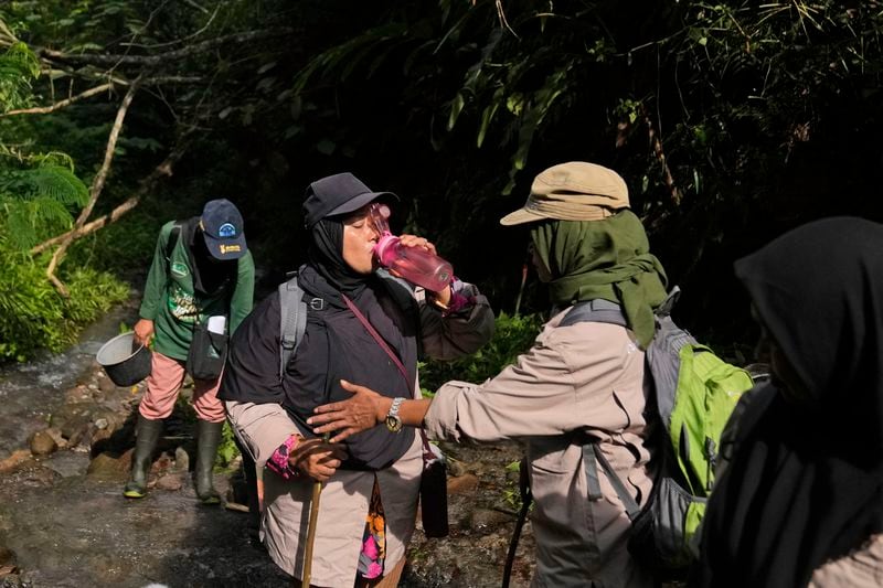 Asmiah, member of female ranger group, drinks from a water bottle during a forest patrol in Damaran Baru, Aceh province, Indonesia, Tuesday, May 7, 2024. The group of forest rangers are defying social norms to lead patrols in the jungle to combat deforestation. (AP Photo/Dita Alangkara)
