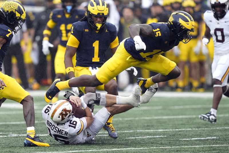 Michigan linebacker Ernest Hausmann (15) jumps over Minnesota quarterback Max Brosmer (16) during the first half of an NCAA college football game, Saturday, Sept. 28, 2024, in Ann Arbor, Mich. (AP Photo/Carlos Osorio)