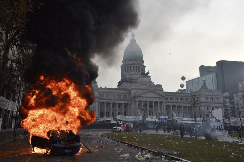 A car burns during clashes between police and anti-government protesters outside Congress, where lawmakers debate a reform bill promoted by Argentine President Javier Milei in Buenos Aires, Argentina, Wednesday, June 12, 2024. (AP Photo/Gustavo Garello)