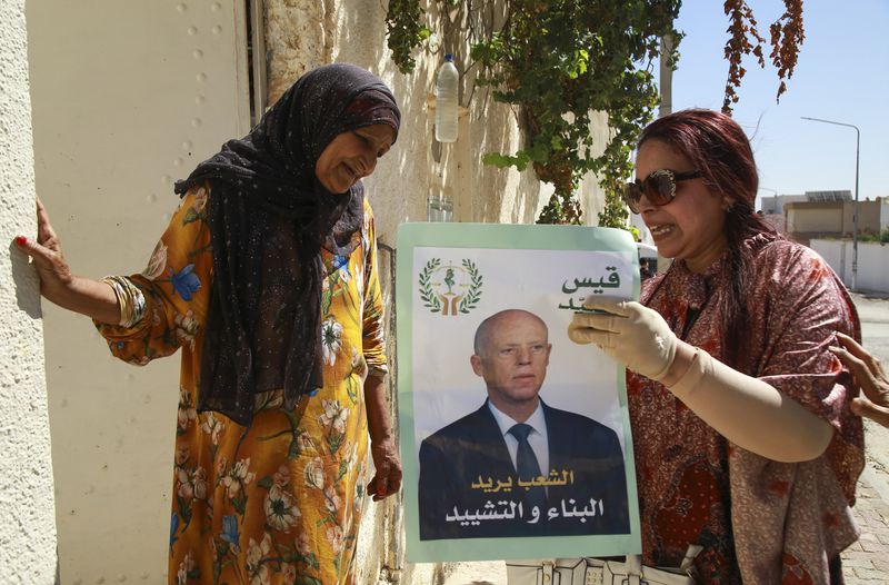 A supporter of Tunisian President and candidate for re-election Kais Saied meets with residents of a neighbourhood during a campaign tour, in Ariana, Tunisia, Thursday, Sept. 26, 2024. (AP Photo/Anis Mili)