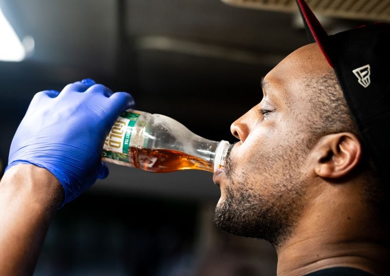 Cornoy Watkins, co-owner of Good As Burgers, takes a drink of sweet tea inside the Good As Burgers food truck outside Bookstore Gallery in Atlanta on July 24. Watkins said the interior can get up to 15 degrees hotter than the outside temperature. (Seeger Gray / AJC)