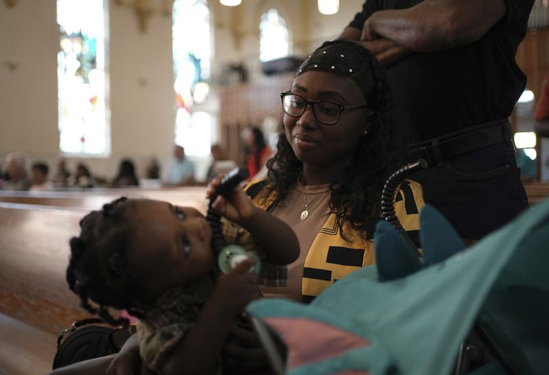 Parishioner Rose Carmelle Bellevue looks at his 1-year-old son during a service at St. Raphael Catholic church in Springfield, Ohio, Sunday, Sept. 15, 2024. (AP Photo/Luis Andres Henao)