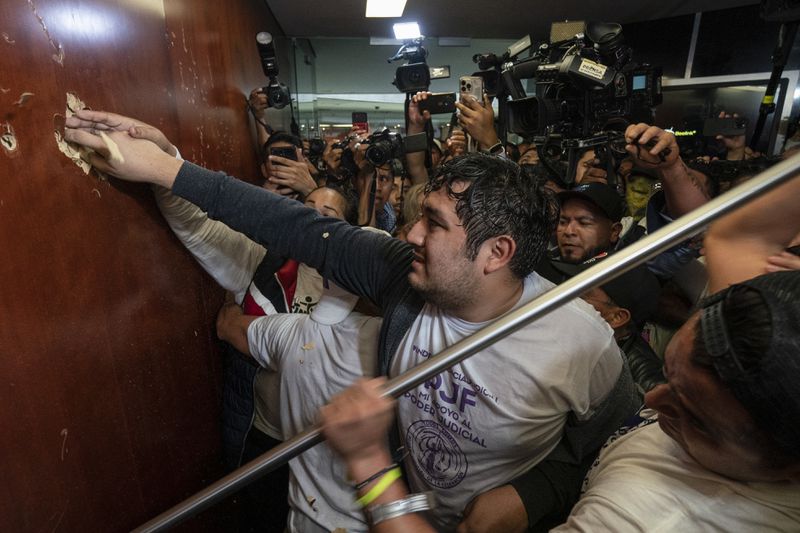 Protesters break into a Senate session in which lawmakers were debating the government's proposed judicial reform, which would make judges stand for election, in Mexico City, Tuesday, Sept. 10, 2024. (AP Photo/Felix Marquez)