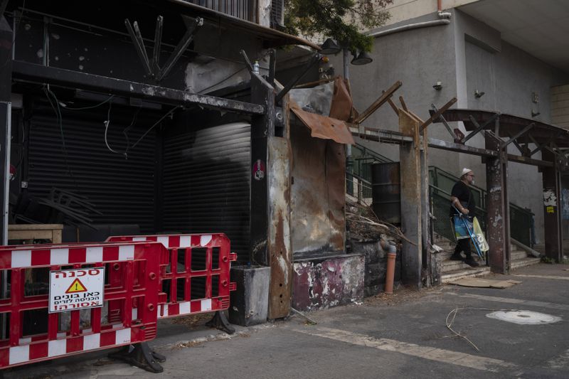 A man walks past a damaged shop, from previous shelling attacks from Lebanon, in Kiryat Shmona, northern Israel, Tuesday, Sept. 17, 2024. (AP Photo/Leo Correa)